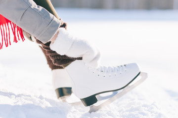 Girl in dress skates mittens tying shoelaces
