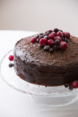 Homemade fresh chocolate birthday cake with organic frozen berries and chips on the top. Crystal plate wiht a nice cake for a party.