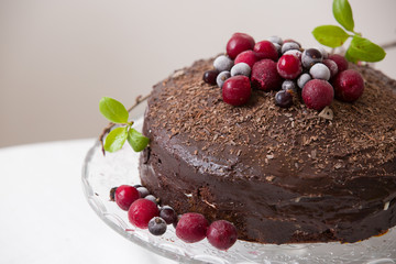 Homemade fresh chocolate birthday cake with organic frozen berries and chips and freash spring leaves on the top. Piece of cake and celebration. Decoration of a birthday cake.