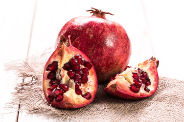 Some red juicy pomegranate, whole and broken, on rustic wooden table