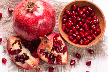 Some red juicy pomegranate, whole and broken, on rustic wooden table