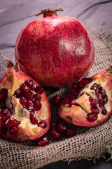Some red juicy pomegranate, whole and broken, on rustic wooden table