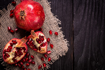 Some red juicy pomegranate, whole and broken, on rustic wooden table