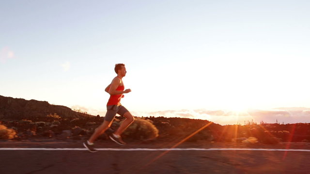 Running runner man athlete training outdoors exercising on mountain road at sunset in amazing landscape nature. Fit handsome athletic male working out for marathon run outside in summer.