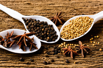 Colorful spices in plastic spoons - coriander seeds, and black p