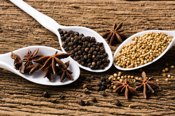 Colorful spices in plastic spoons - coriander seeds, and black p