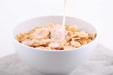 Milk flows in a bowl with corn and rice flakes