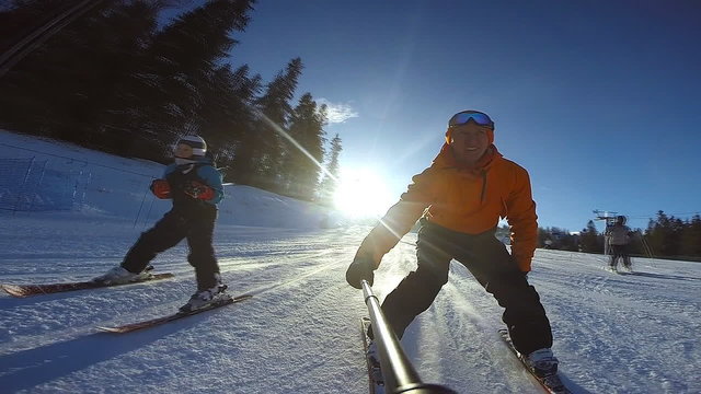 Little boy slides on alpine skis with his father