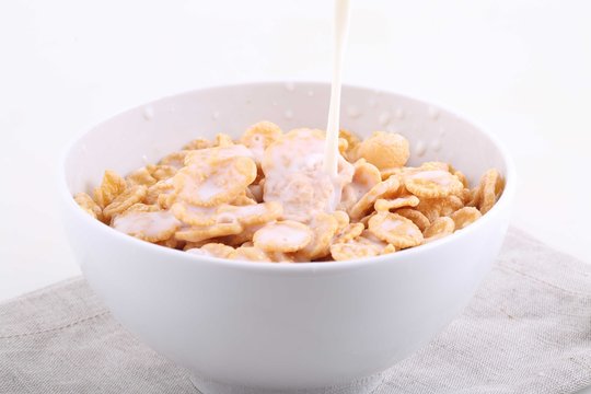 Milk flows in a bowl with corn and rice flakes