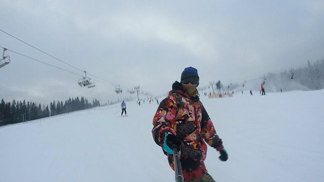 Man riding on snowboard with selfie stick in his hand 