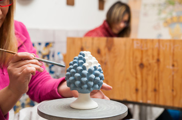 A pottery decorator painting a typical ceramic pine cone in his work table in Caltagirone, Sicily