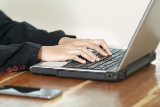 Hands of businesswoman  on the keyboard of her laptop computer.