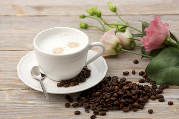 A cup of coffee, coffee beans and eustoma flowers