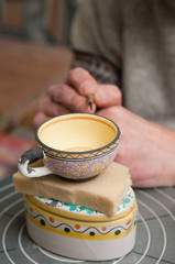 A pottery decorator finishing a ceramic small cup with floral motifs in his work table in Caltagirone, Sicily