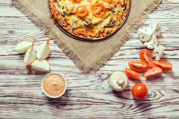 Italian pizza with pepperoni, tomatoes on wooden table. Top view with copy space