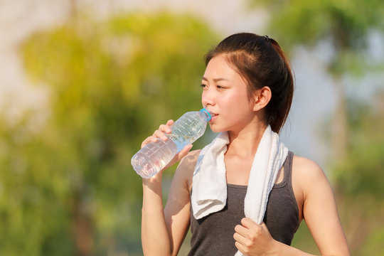 Sporty woman asia drinking water outdoor on sunny day