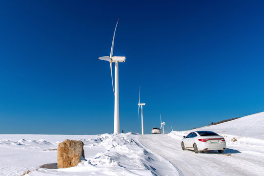 Wind turbine and Car with blue sky in winter landscape.