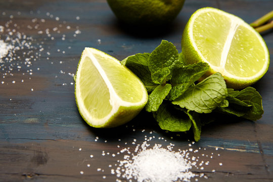 mint leaves, ice, sugar and lime on dark  wooden background