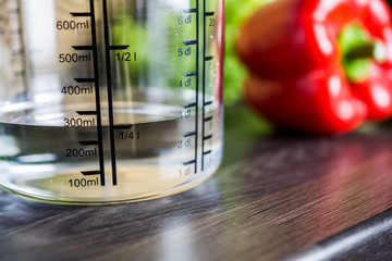 250ccm / 1/4 Liter / 250ml Of Water In A Measuring Cup On A Kitchen Counter With Food