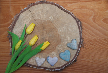 rustikales Holzscheibe mit gelben Tulpen und Speckstein-Herzen,