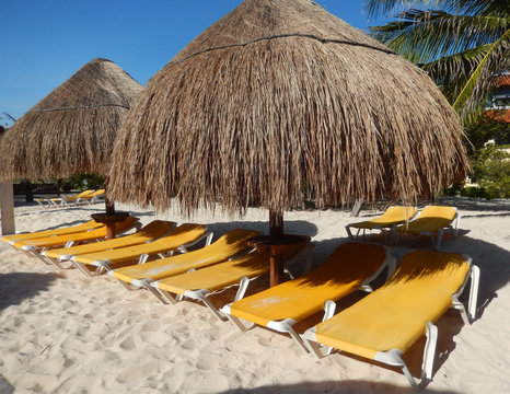 Straw umbrellas and folding chairs on a Caribbean beach in Riviera Maya, Mexico, for travel background