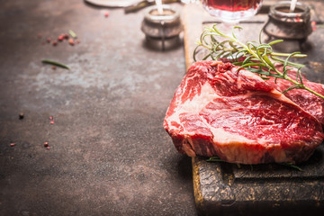 Close up of raw fresh meat Ribeye Steak with herbs and spices on dark rustic metal background,...