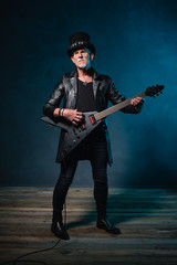 Fototapeta premium Heavy metal senior man with electric guitar in front of dark blu