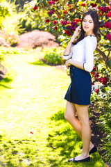 Young beautiful woman with long straight dark hair posing in spring garden