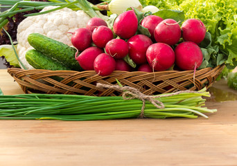 Spring vegetables in basket: radish, cucumber, chives and cauliflower