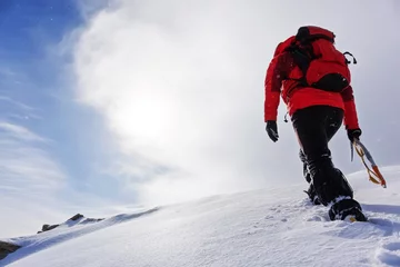 Fototapeten Mountaineer climbing a snowy peak in winter season. © rcaucino