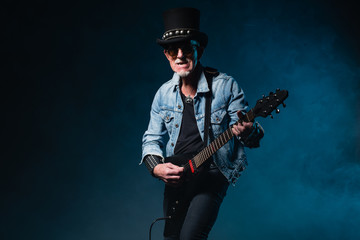 Fototapeta premium Heavy metal senior man with electric flying-v guitar in front of