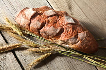 rustic crusty bread and wheat ears on a dark wooden table