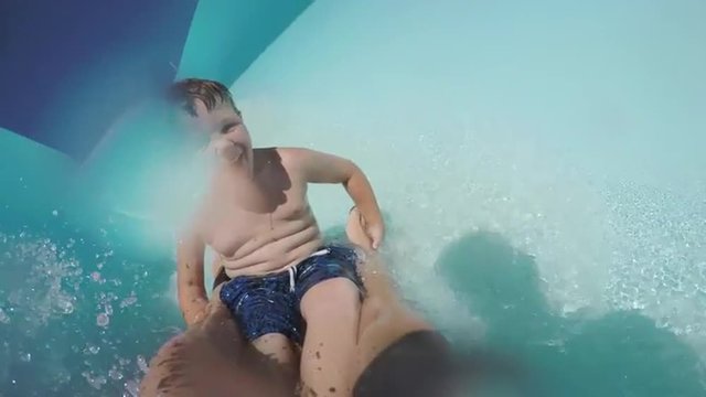 Happy young boy going down curved waterslide in slow motion Cape Town