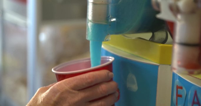 A concession stand worker pours a slushie from a frozen drink machine.