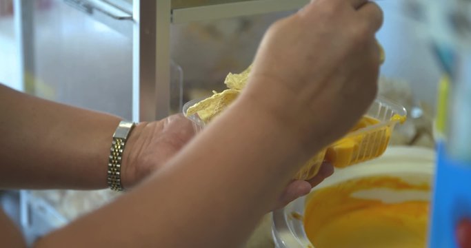 A server adds nacho cheese to a plastic serving container. 