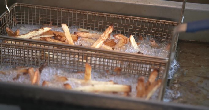 French Fries Sizzle In The Grease Of A Commercial Deep Fryer.