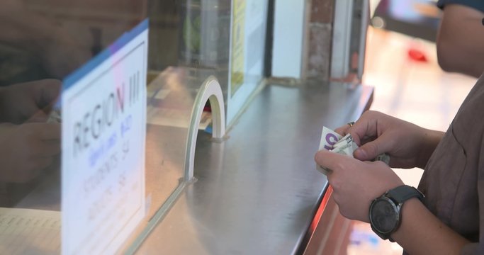 Patrons purchase tickets at a ticket booth.