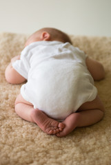 Newborn baby sleeping on sheepskin rug with feet showing