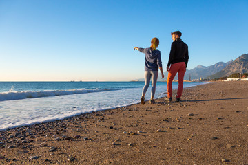 Man and Woman walking on Beach and enjoying Sea View