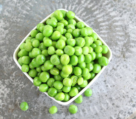 Cooked peas in a bowl on a vintage metal background.