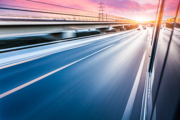 Obraz premium Car driving on freeway at sunset, motion blur