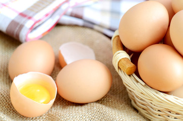 Wicker basket with eggs and raw egg on a linen tablecloth