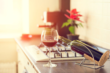 Glass of red wine with bottle on kitchen worktop
