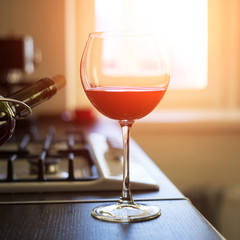 Glass of red wine with bottle on the kitchen table