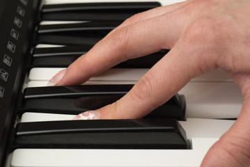 Fototapeta na wymiar Woman hand playing a MIDI controller keyboard synthesizer close up