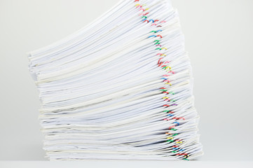 Overload pile of paperwork with colorful paperclip on white table