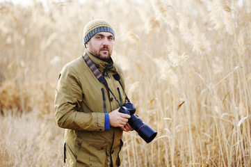 a man with a camera on a background of yellow high grass. Photog