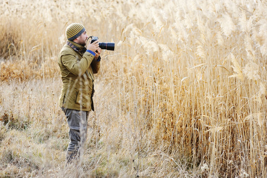 a man with a camera on a background of yellow high grass. Photog
