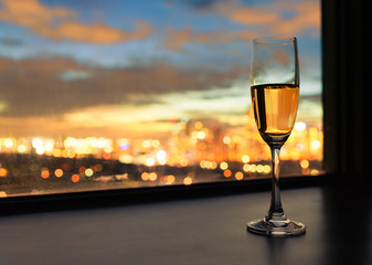Glass of champaign next t window at sunset. 