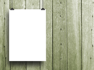 Close-up of one hanged paper sheet with clip on green wooden boards background